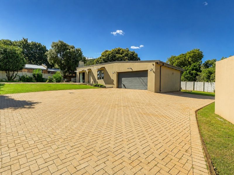 Front exterior view of the property featuring a spacious paved driveway, a single garage, and a well-maintained garden area.