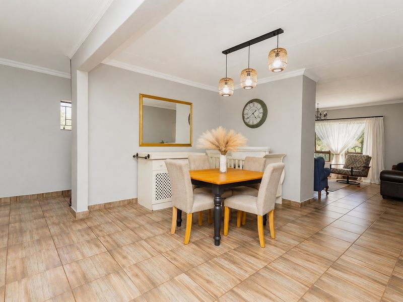 Spacious open-plan dining area featuring neutral wall tones, modern pendant lighting, and durable tiled flooring, seamlessly flowing into the adjacent living space.