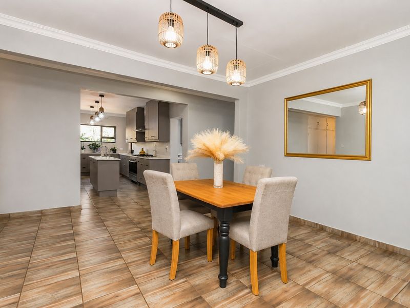 Open-plan dining area featuring tiled floors and crown molding, flowing seamlessly into a modern kitchen with island and built-in appliances.