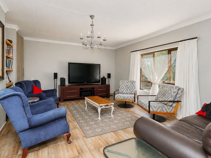 A well-maintained living room featuring tiled flooring, coved cornicing, a decorative chandelier, and built-in shelving units.