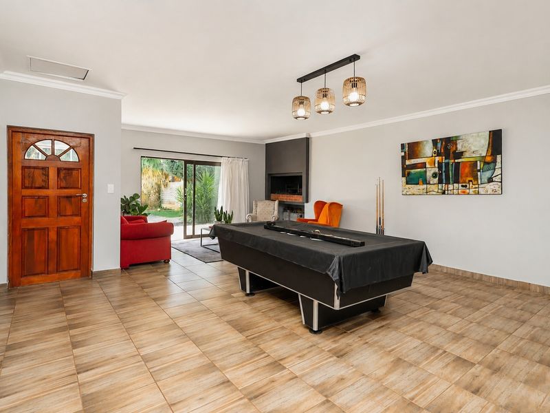 Spacious living area featuring tiled flooring, a built-in fireplace, and direct access to the garden through sliding glass doors.