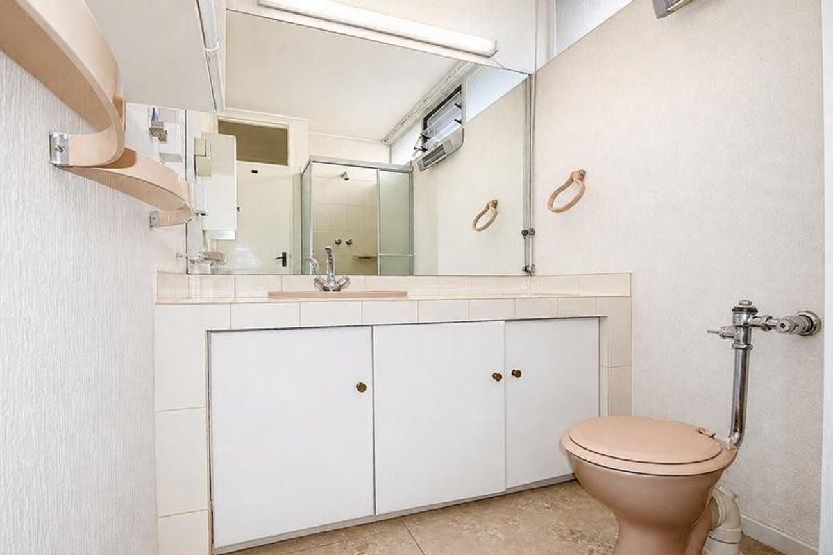 A dated bathroom featuring a vanity cabinet with integrated sink, a large wall mirror, and a separate shower enclosure.