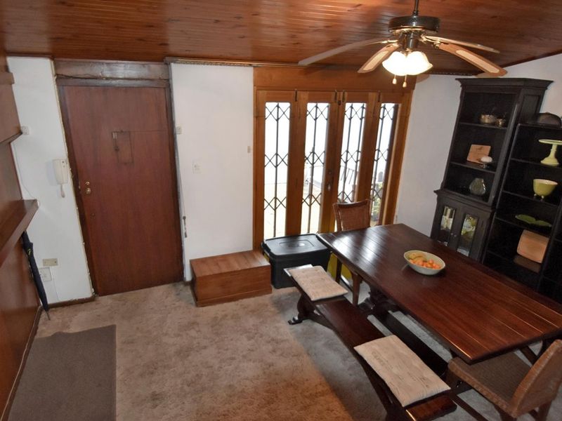 Dining area featuring a timber ceiling, ceiling fan, and direct access to the exterior through a security gate.