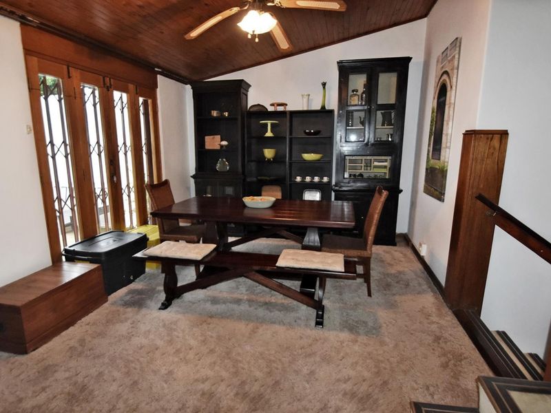 Dining room featuring a timber-clad vaulted ceiling, ceiling fan, and timber-framed folding doors leading to the exterior.
