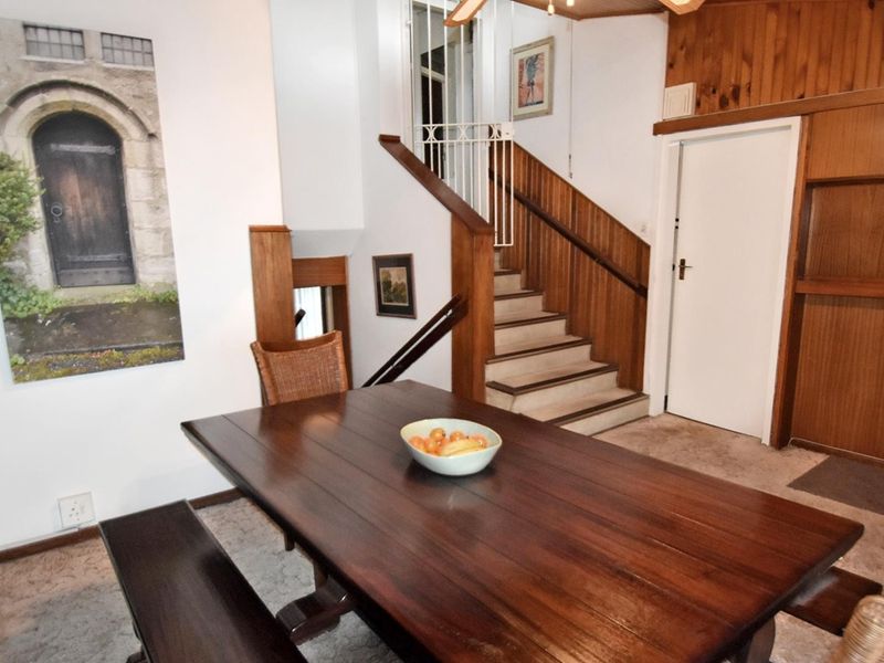 Dining area featuring a staircase with wooden paneling and built-in shelving, showcasing a dated interior design ready for modernization.