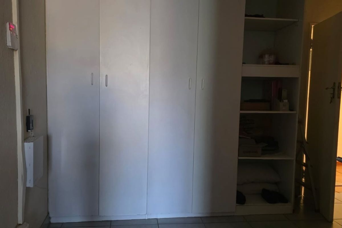 A bedroom featuring built-in cupboards and tiled flooring, offering a functional storage solution within the living space.