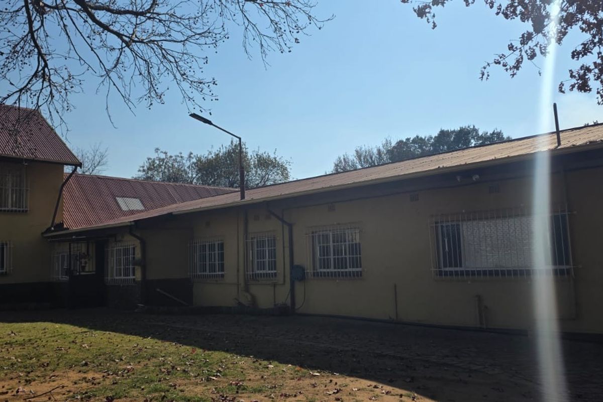 Rear view of the farm property featuring a multi-level structure with corrugated metal roofing and security bars on the windows.