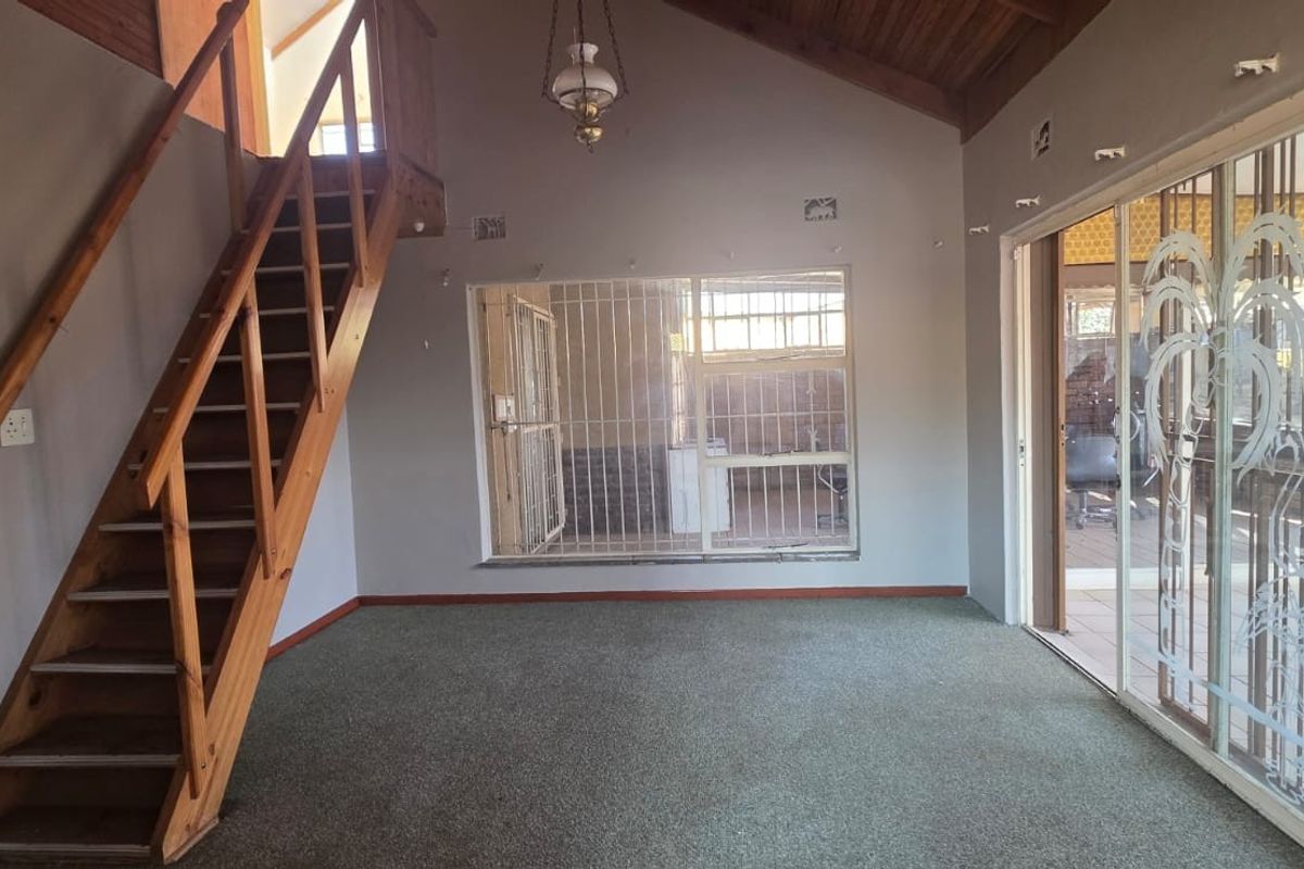 Spacious living area featuring a timber staircase, vaulted wood-paneled ceiling, and large sliding glass doors leading to an outdoor space.
