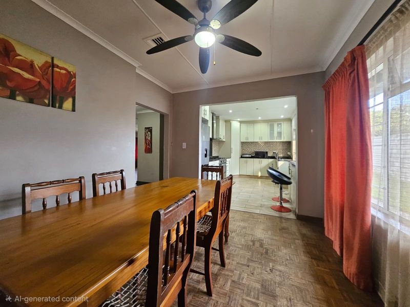 Open plan dining area featuring parquet flooring and a ceiling fan, flowing into a functional kitchen with built-in cabinetry and tiled flooring.