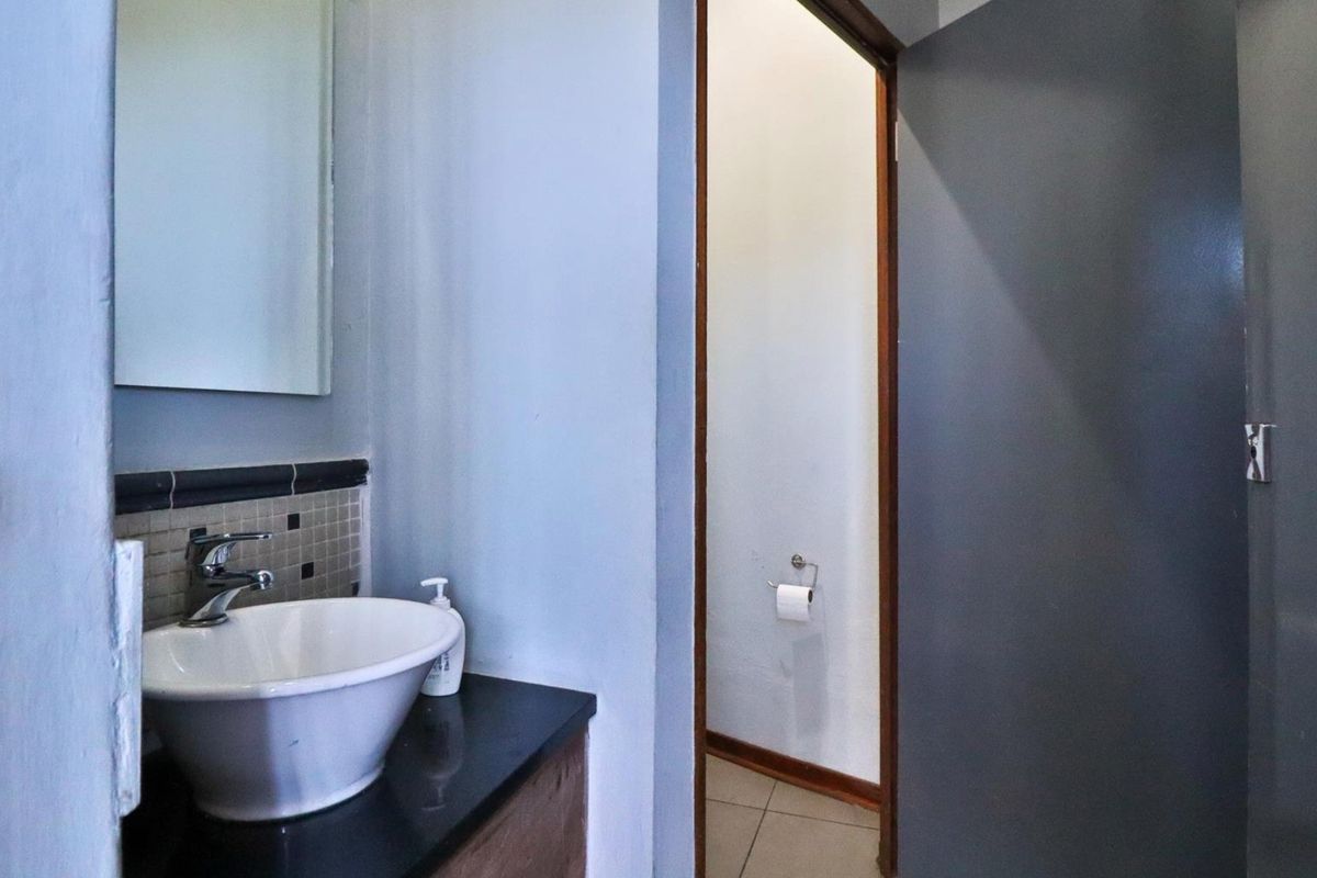 A functional bathroom featuring a modern vessel sink on a dark vanity countertop with an adjacent private toilet area.