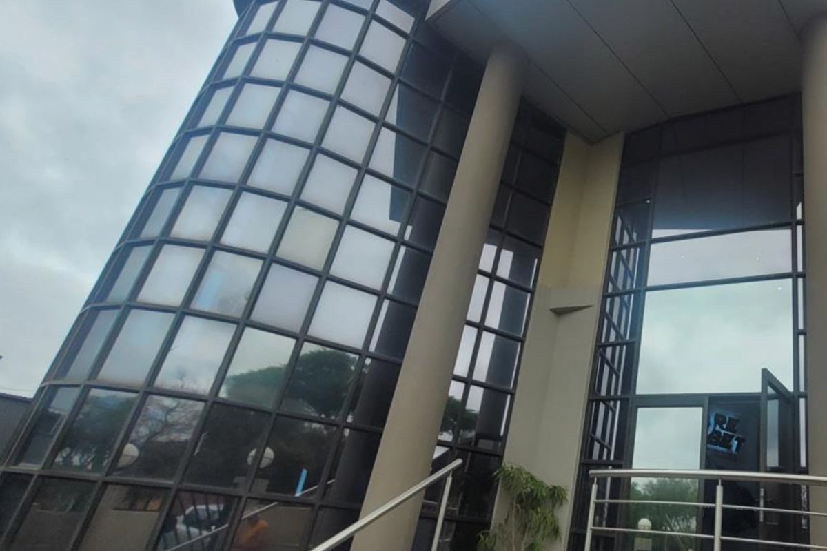 Modern commercial building facade featuring a prominent curved glass curtain wall, structural columns, and a glass entrance.