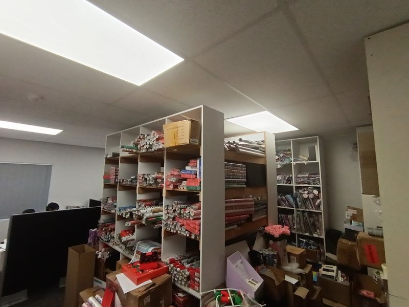 An office space featuring a suspended ceiling with recessed lighting and integrated floor-to-ceiling shelving units for storage.