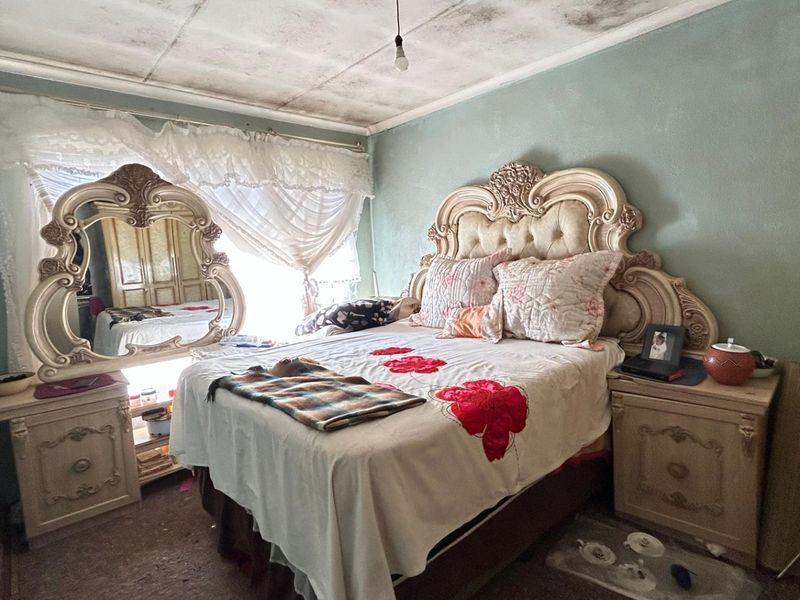 A bedroom featuring a standard layout with visible ceiling damage and worn flooring, requiring maintenance and cosmetic updates.