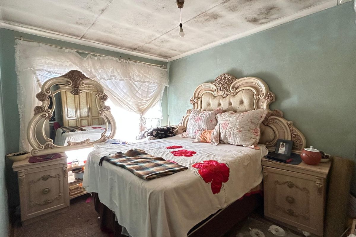 A bedroom featuring a built-in wardrobe and significant ceiling staining, requiring maintenance and cosmetic updates to restore the space.