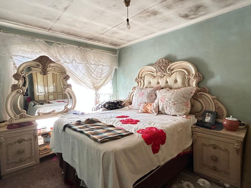 A bedroom featuring a built-in wardrobe and significant ceiling staining, requiring maintenance and cosmetic updates to restore the space.