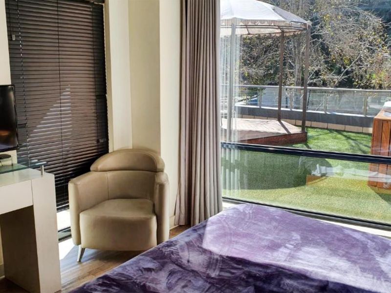A bright bedroom featuring large floor-to-ceiling windows with direct access to an outdoor patio area.