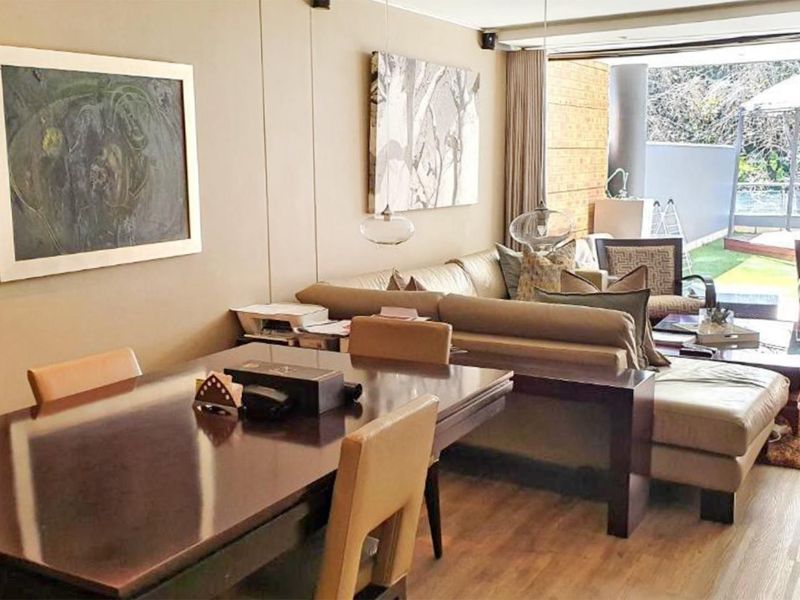 Open-plan living and dining area featuring laminate flooring and large sliding glass doors that provide seamless access to the outdoor patio space.