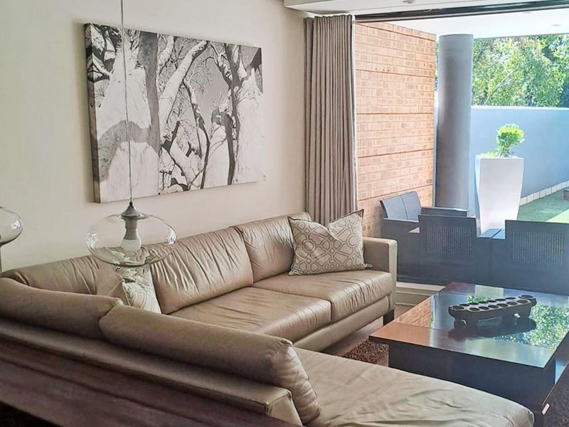 A well-lit living room featuring large sliding glass doors that provide seamless access to an outdoor patio area.