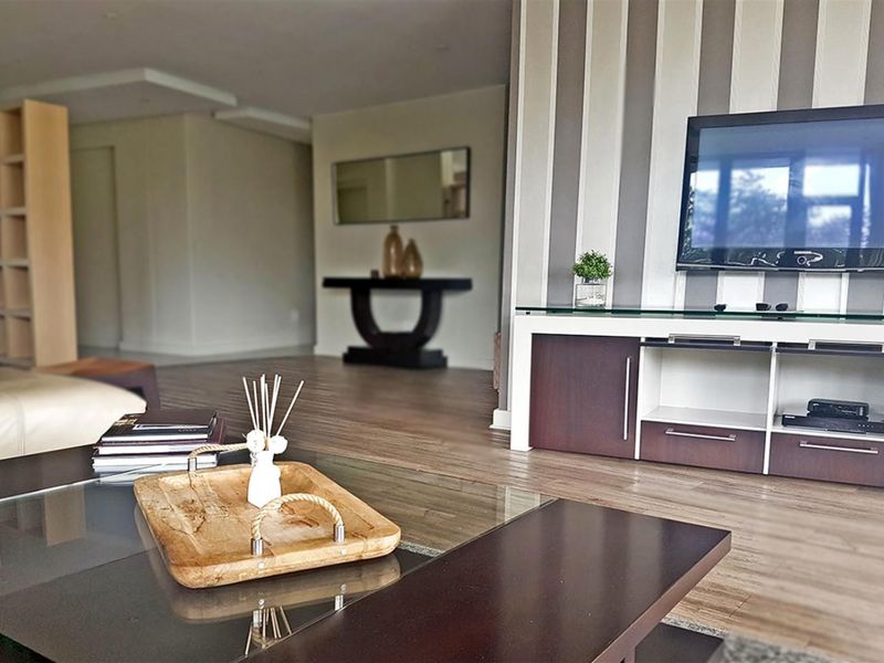 Spacious living area featuring modern laminate flooring, a decorative striped feature wall, and recessed ceiling lighting.