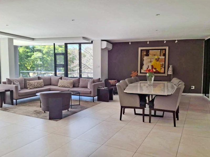 Spacious open-plan living and dining area featuring large format floor tiles, recessed lighting, and expansive floor-to-ceiling glass doors providing ample natural light.