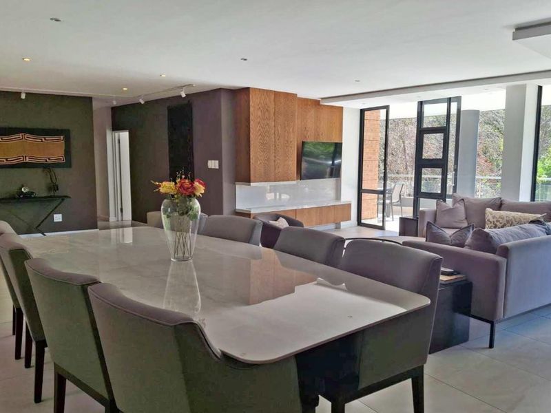 Spacious open-plan living and dining area featuring modern floor tiles, recessed lighting, and seamless access to an outdoor balcony through large sliding glass doors.