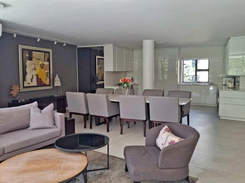 Spacious open-plan living and dining area featuring modern kitchen cabinetry, tiled flooring, and recessed lighting, creating a seamless flow for contemporary apartment living.