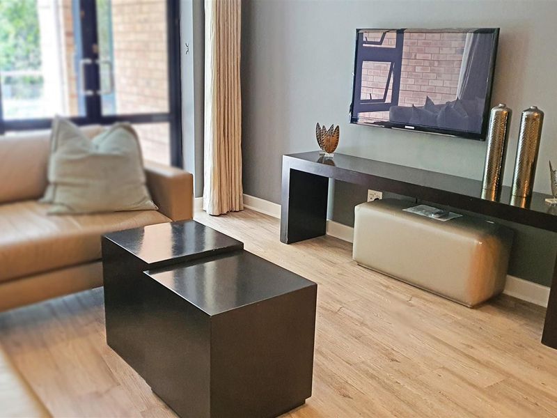 A well-maintained living room featuring modern laminate flooring and a large sliding glass door providing natural light.