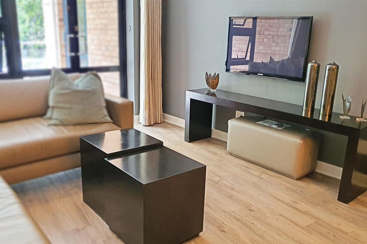 A well-maintained living room featuring modern laminate flooring and a large sliding glass door providing natural light.