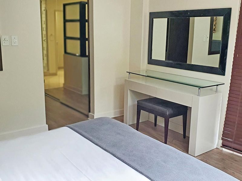 A well-maintained bedroom featuring laminate flooring, neutral wall finishes, and an adjoining en-suite bathroom area.