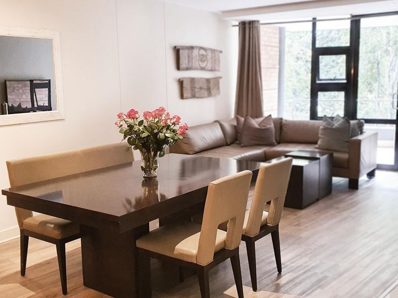 An open-plan living and dining area featuring laminate flooring and large glass sliding doors that provide ample natural light.