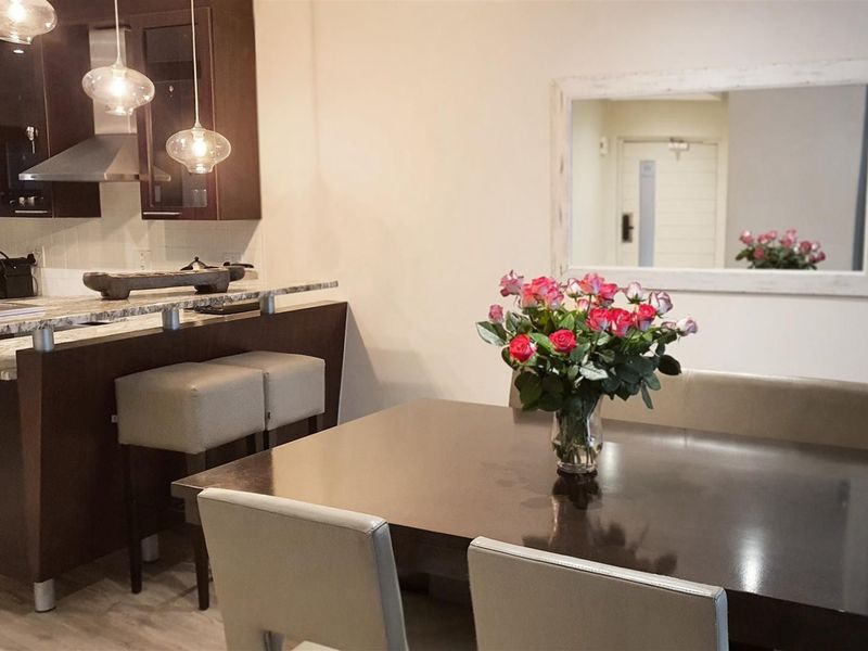 Open plan dining and kitchen area featuring dark wood cabinetry, granite countertops, a breakfast bar, and modern pendant lighting.