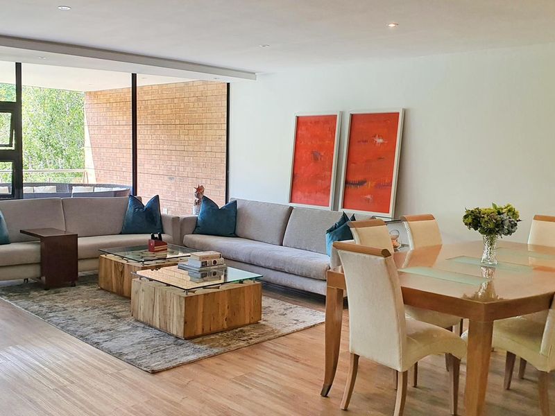 Spacious open-plan living and dining area featuring hardwood flooring, recessed lighting, and large sliding glass doors leading to an outdoor balcony.
