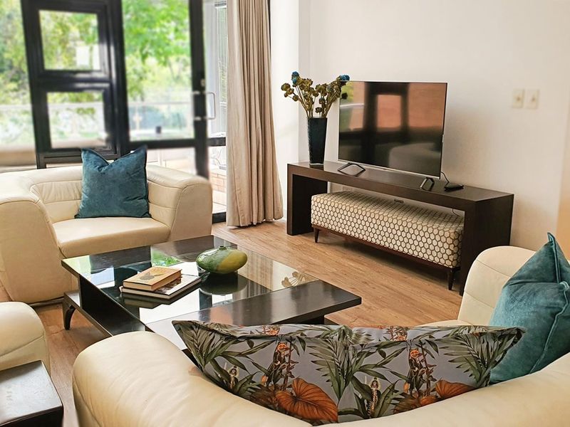 A bright and inviting living room featuring modern laminate flooring and large glass sliding doors that provide ample natural light and outdoor access.