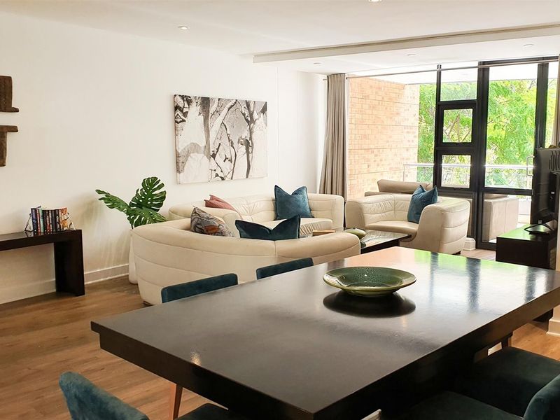 Spacious open-plan living and dining area featuring modern laminate flooring, recessed lighting, and large sliding glass doors leading to a private balcony.