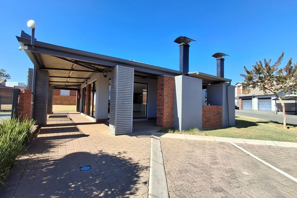 A well-maintained covered patio area featuring brick paving, built-in braai facilities, and modern architectural brick and metal detailing.