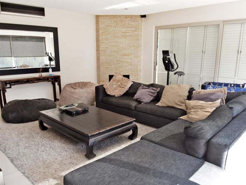 Spacious living room featuring a stone-clad fireplace, split-system air conditioning, and large sliding glass doors providing access to the outdoor area.