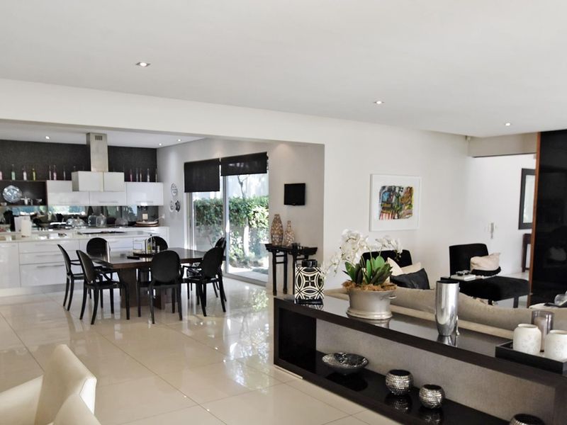 Spacious open-plan living and dining area featuring polished porcelain tiles, recessed lighting, and a modern kitchen with integrated cabinetry and extractor fan.