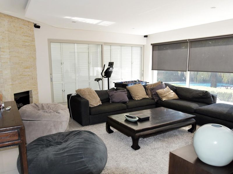 Spacious living room featuring a stone-clad fireplace, large sliding glass doors with roller blinds, and neutral tiled flooring.
