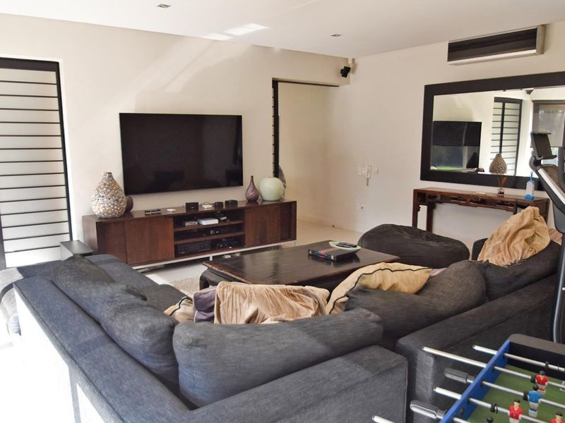 A spacious living room featuring recessed lighting, a wall-mounted air conditioning unit, and large sliding glass doors providing access to the exterior.