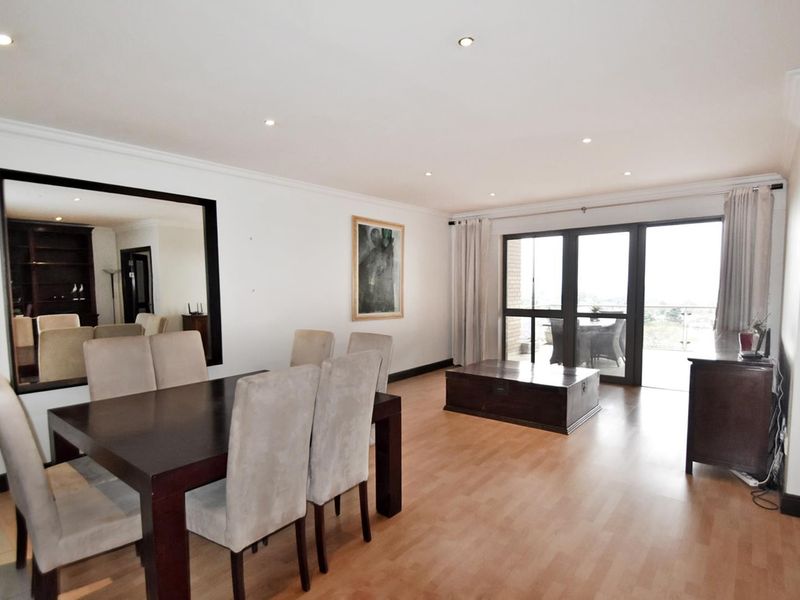 Spacious dining area featuring laminate flooring, recessed downlighting, and large sliding glass doors providing access to the balcony.