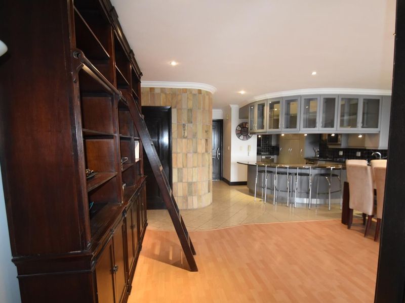 Open plan living area featuring a kitchen with island, stone feature wall, and built-in cabinetry, seamlessly connecting to the dining space.