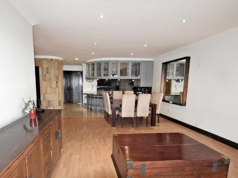 Spacious open-plan living and dining area featuring a stone accent wall, recessed lighting, and a functional kitchen with a breakfast bar.