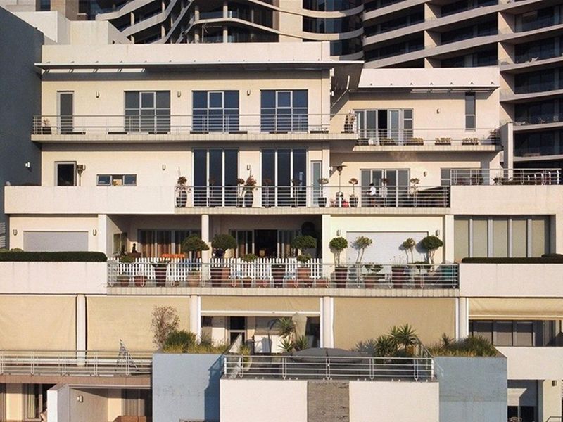 A multi-level apartment building facade featuring tiered balconies with metal railings and large sliding glass doors overlooking the outdoor terrace areas.