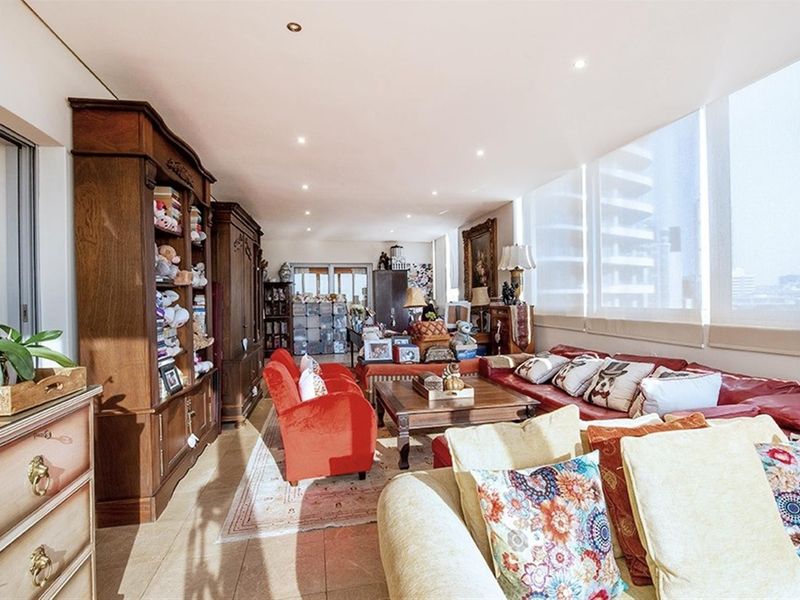 Spacious living room featuring large floor-to-ceiling windows that provide ample natural light and tiled flooring throughout.