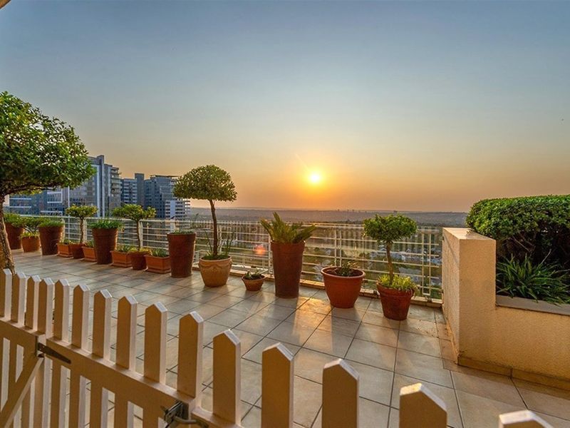 Spacious elevated balcony featuring tiled flooring, a protective metal balustrade, and a picket fence, offering expansive sunset views.