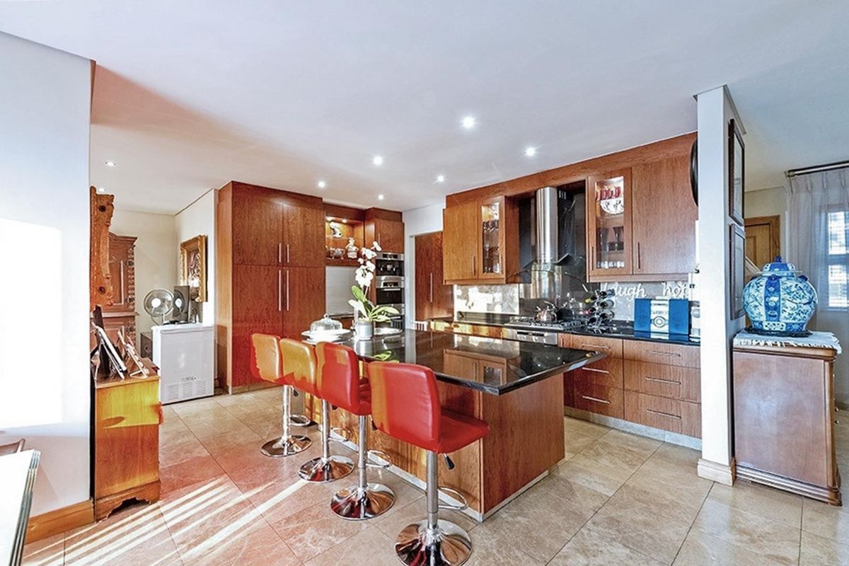 A functional kitchen featuring wooden cabinetry, a central island with granite countertops, built-in oven, and recessed lighting, offering a classic aesthetic.