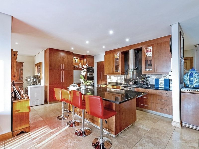 A functional kitchen featuring wooden cabinetry, a central island with granite countertops, built-in oven, and recessed lighting, offering a classic aesthetic.