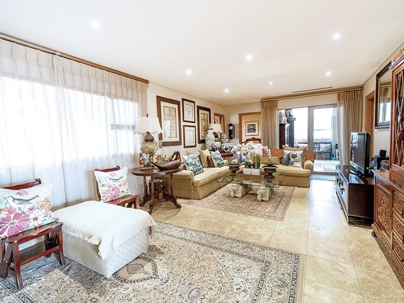 Spacious living room featuring neutral tiled flooring, recessed downlighting, and large sliding glass doors providing access to an outdoor area.