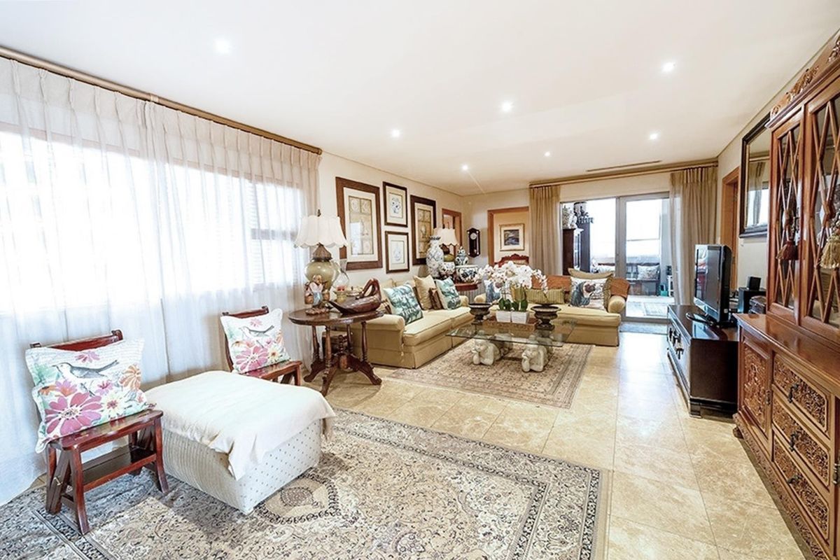 Spacious living room featuring neutral tiled flooring, recessed downlighting, and large sliding glass doors providing access to an outdoor area.