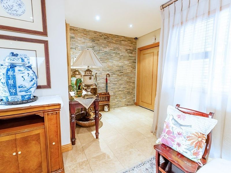 Welcoming entrance hall featuring a textured stone cladding feature wall, neutral tiled flooring, and recessed downlighting.